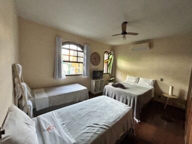 Vista do quarto da pousada naturaleza com uma cama de casal e duas de solteiro com ar condicionado e televisão